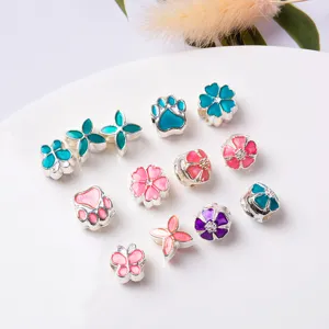Close-up of DIY enamel silver charms, colorful flower, paw, and butterfly beads for bracelets.
