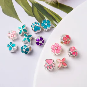 Detailed view of colorful enamel DIY charm beads with flower and paw designs for bracelets.