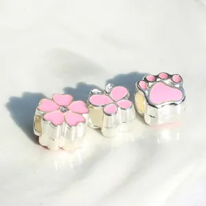 Close-up detail of silver alloy enamel beads featuring cute flower, butterfly, and paw designs.