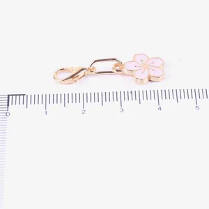 Close-up of a gold-tone lobster clasp with a cute pink enamel cherry blossom charm.