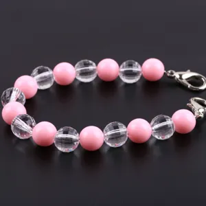 Bracciale di perle rosa e trasparenti con perline e chiusure metalliche, dettaglio gioiello.