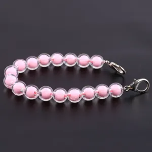Vista dettagliata di un braccialetto di perle in resina trasparente con cuori rosa.
