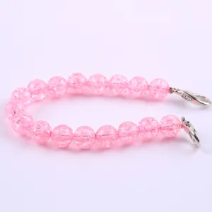 Primo piano dettagliato del cinturino di perle rosa screpolate con ganci metallici.