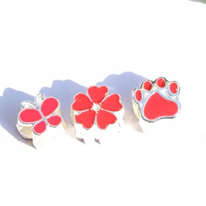 Close-up of alloy charm beads with red enamel butterfly, clover and paw designs.