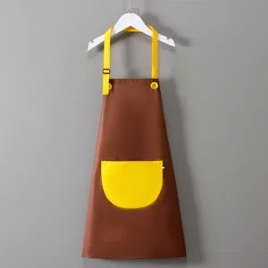 Dettaglio grembiule da pittura per bambini, marrone con tasca gialla e tracolla regolabile.