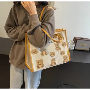 Détail sac cabas en toile, imprimé ours mignon, style sac à main décontracté avec bordure jaune.