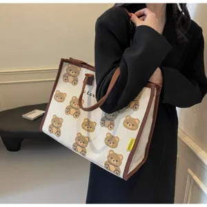 Gros-plan du sac cabas en toile avec motif d'ours mignon et finitions marron élégantes.