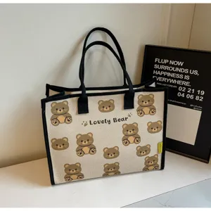 Vue détaillée du charmant sac cabas en toile avec motif d'ours et poignées noires.