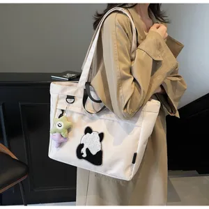 Dettaglio della borsa in tela bianca con ricamo di panda carino e ciondolo a stella.