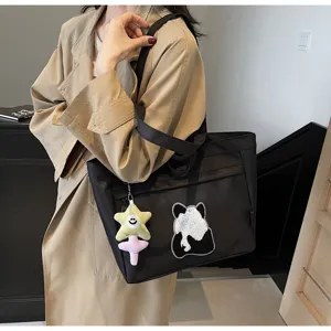 Dettaglio della borsa shopper in tela nera con ricamo panda e ciondolo stella di peluche carino.
