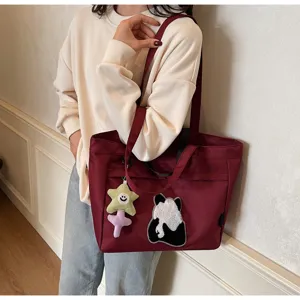 Primo piano della borsa tote in tela bordeaux con ricamo panda carino e ciondolo a stella.