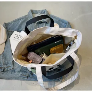 Dettaglio borsa shopper in tela bianca con una grande capienza e tasche interne.
