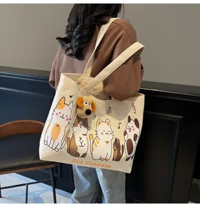 Canvas tote bag detail view showing cute cat print and plush pendant, casual style.