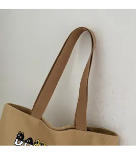 Vue détaillée de sac cabas en toile montrant une bandoulière marron robuste et un joli imprimé.