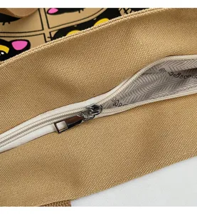 Gros plan détaillé du sac cabas en toile avec fermeture éclair blanche et doublure chat mignon.