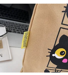 Détail de sac cabas en toile avec joli motif de chat noir et étiquette jaune sur bureau.