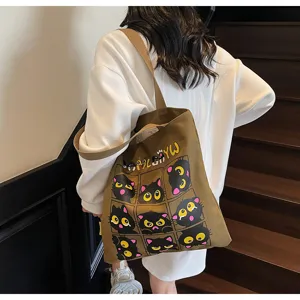 Détail de sac cabas en toile avec imprimé grille de chats noirs mignons et bandoulière.