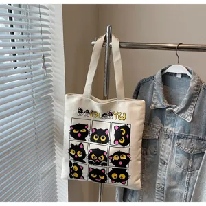 Vue détaillée d'un sac cabas en toile avec de jolis imprimés de chats noirs et texte.