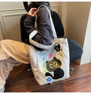 Détail du sac cabas en toile avec imprimé de chat mignon et anses blanches solides.