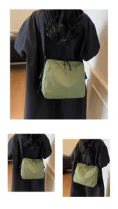 Detail view of the green plaid crossbody shoulder bag showing texture, strap, and wear style.