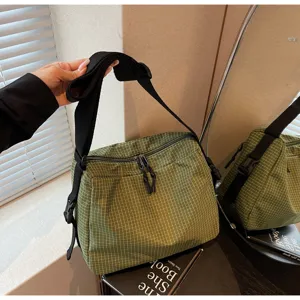Green grid crossbody bag detail showing the adjustable black strap and sturdy zipper closure.