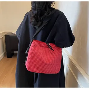 Detailed shot of red plaid crossbody bag scene, showing fabric texture and strap design.