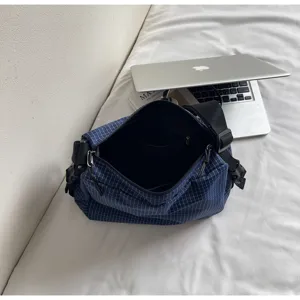 Detail shot of casual blue grid crossbody shoulder bag with zipper and adjustable strap.