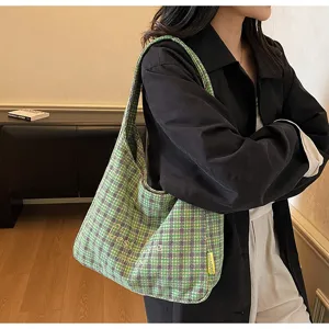 Detail view of the green plaid wool underarm bag worn by model, showcasing cozy texture and embroidery.