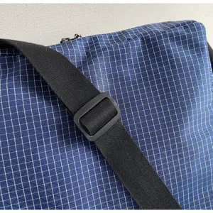 Detailed view of a casual blue grid crossbody bag with black adjustable strap and buckle.