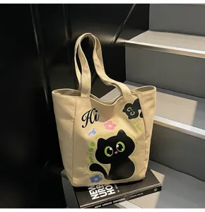 Vue détaillée du sac cabas en toile avec motif de chat noir et lanière d'épaule.