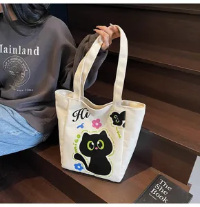 Vue détaillée du sac cabas en toile avec chat noir dessin animé mignon et poignées résistantes.