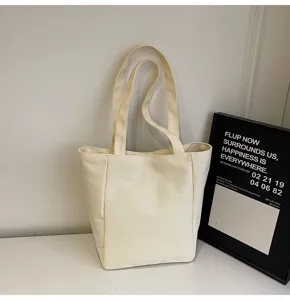 Détail du sac cabas en toile montrant des poignées doubles robustes et un design épuré blanc.