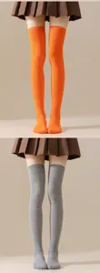 Primer plano de calcetines altos lisos en naranja y gris combinados con falda plisada.