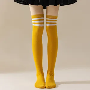 Close-up detail of yellow over-the-knee thigh high socks with triple white stripes.