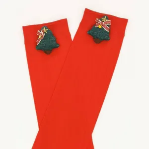 Calze sopra il ginocchio rosse con graziosi inserti in tessuto di albero di Natale festivo.