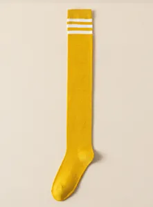 Detail view of yellow over the knee socks featuring classic white triple stripes design.