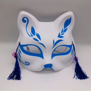Vue détaillée du masque de renard kitsune blanc japonais avec des motifs bleus et des pompons.