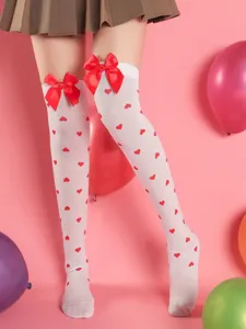 Close-up detail of white over-the-knee socks with red heart print and bows for date party.