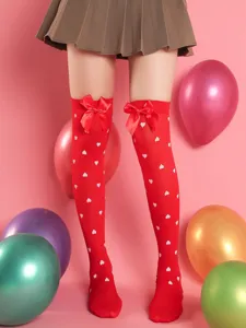 Red over-the-knee socks detail featuring cute heart print and sweet satin bow decoration.