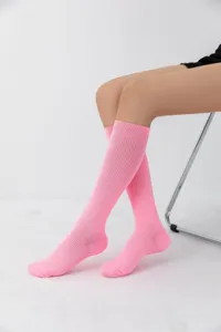 Vista detallada de calcetines altos rosa acanalados con tejido elástico cómodo y suave.