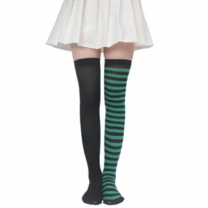 Primo piano di calze lunghe spaiate con righe nere e verdi per feste di Halloween.