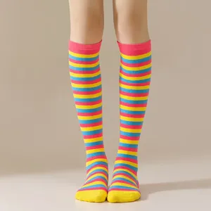 Detalle de calcetines altos a rayas de colores con diseño en rosa, amarillo y azul.