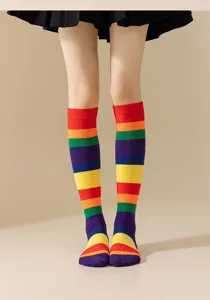 Primer plano detallado de calcetines altos a rayas de arcoíris coloridos usados por modelo.