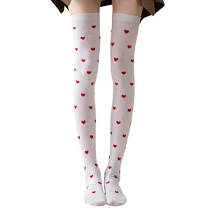 Close-up detail view of white over-the-knee socks featuring cute red heart prints.