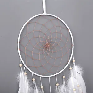 Detalle de atrapasueños hecho a mano con red de alambre de cobre y plumas blancas.