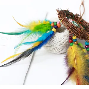 Detailed view of handmade dream catcher hanging decoration with colorful feathers and wooden beads.
