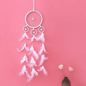 Handmade white dream catcher wall hanging with soft pink feathers for cozy home decor.