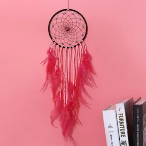 Pink dreamcatcher hanging ornament with feathers and beads for home wall decor.