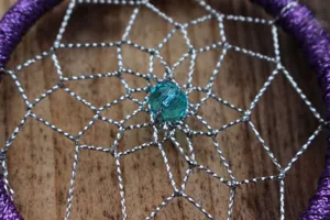 Handmade dream catcher detail shot featuring purple ring and blue center crystal bead.