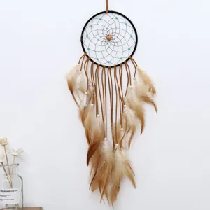 Detailed shot of wall dream catcher featuring black ring, leather cords and soft feathers.